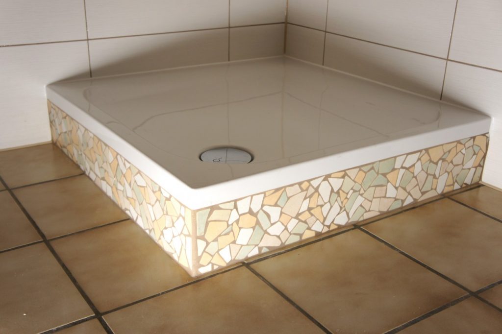 Duschtasse mit Mosaikfliesen in einem gefliesten Badezimmer